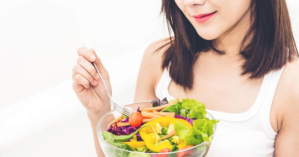 beautiful lady eating a bowl of salad